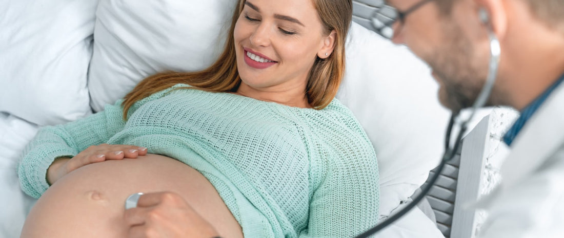 Pregnant woman in blue hospital gown holding her belly