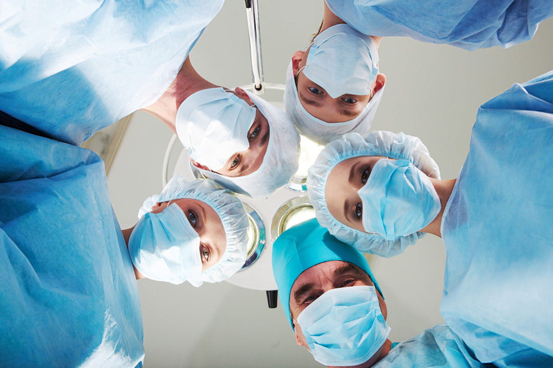 Group of surgeons looking at patient in hospital bed.
